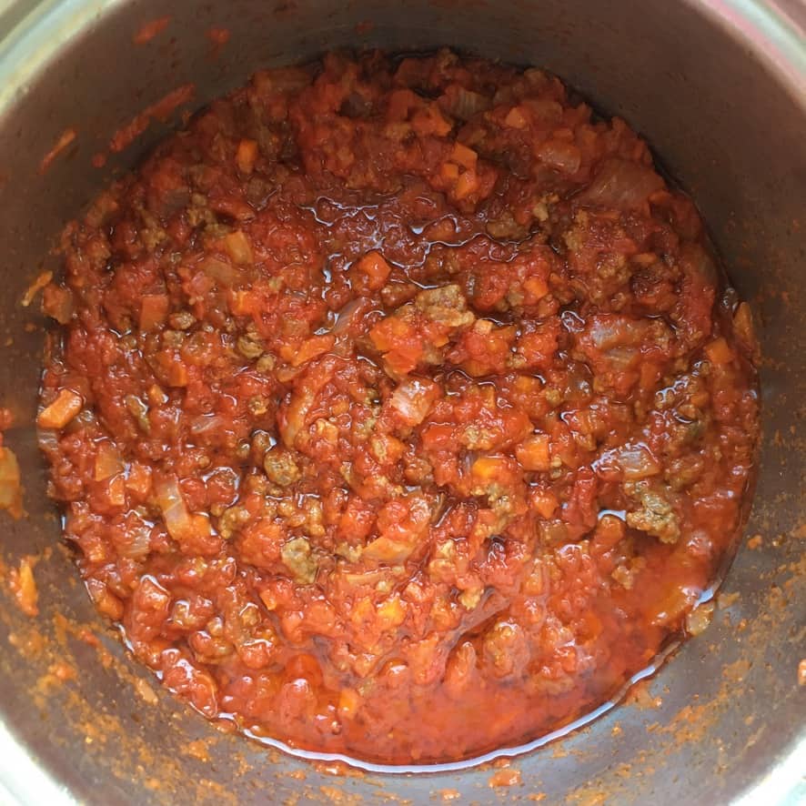 deep red tomato sauce with ground beef, diced onions, celery, and carrots with olive oil