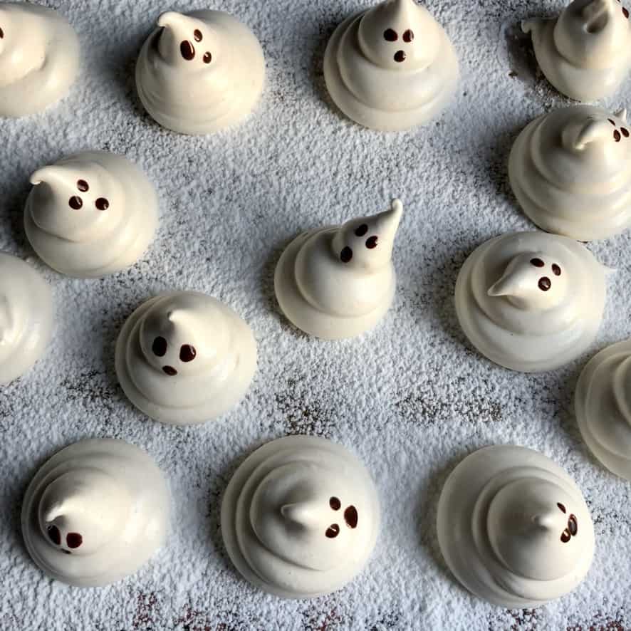 painted ghost marshmallows on a dusted baking tray