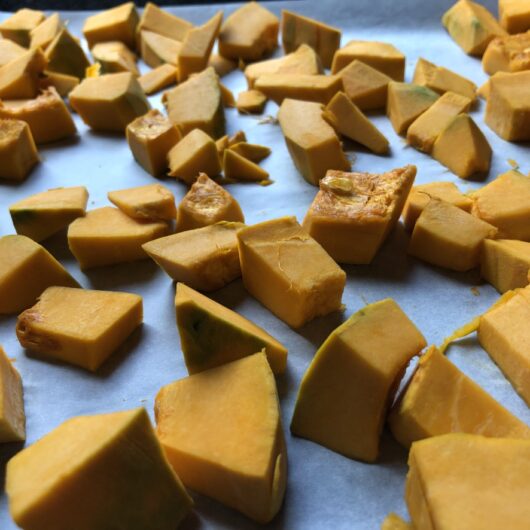 raw diced kabocha squash on parchment lined baking sheet