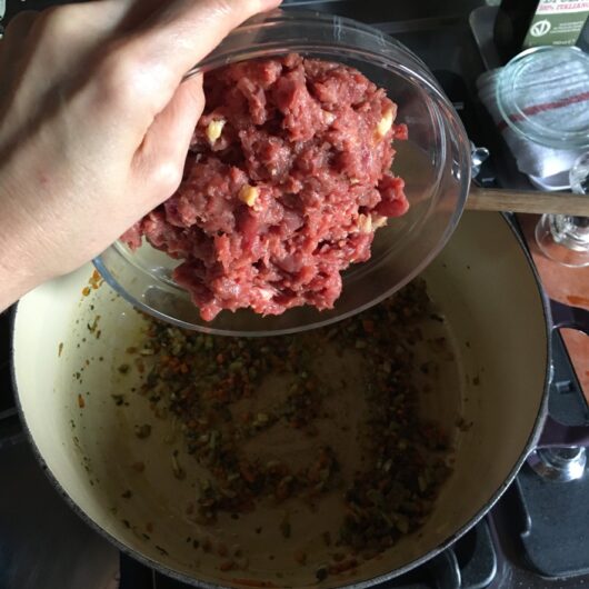 adding raw duck meat to the softened soffritto and herbs