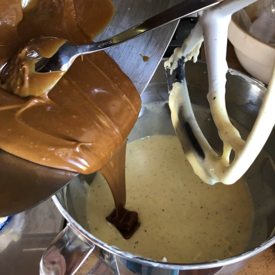 pouring white chocolate caramel sauce into the cheesecake batter
