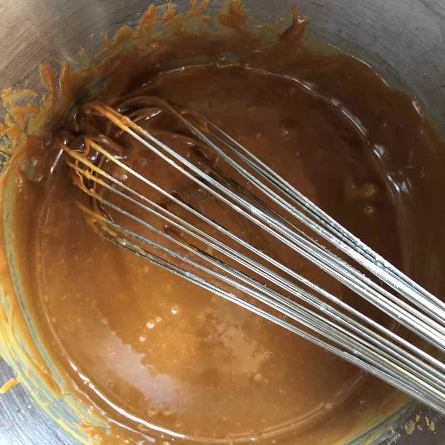 a whisk in a perfectly smooth white chocolate caramel
