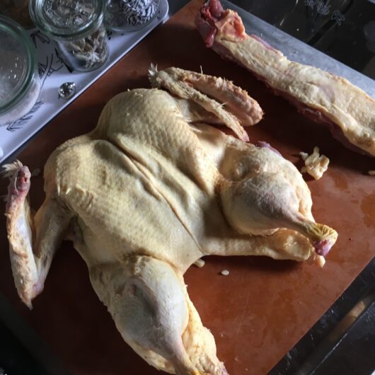 duck that's been butterflied and lying on a cutting board