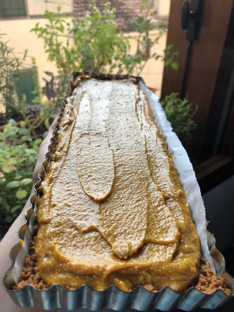 pecan pumpkin tart in the sunlight with only the filling added at this point