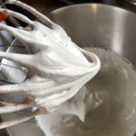 a whisk with super fluffy marshmallow mixture on then end in stiff peaks