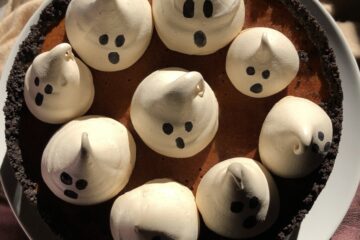 a whole cheesecake topped with cute fat ghost meringues