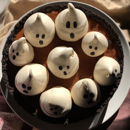 a whole cheesecake topped with cute fat ghost meringues
