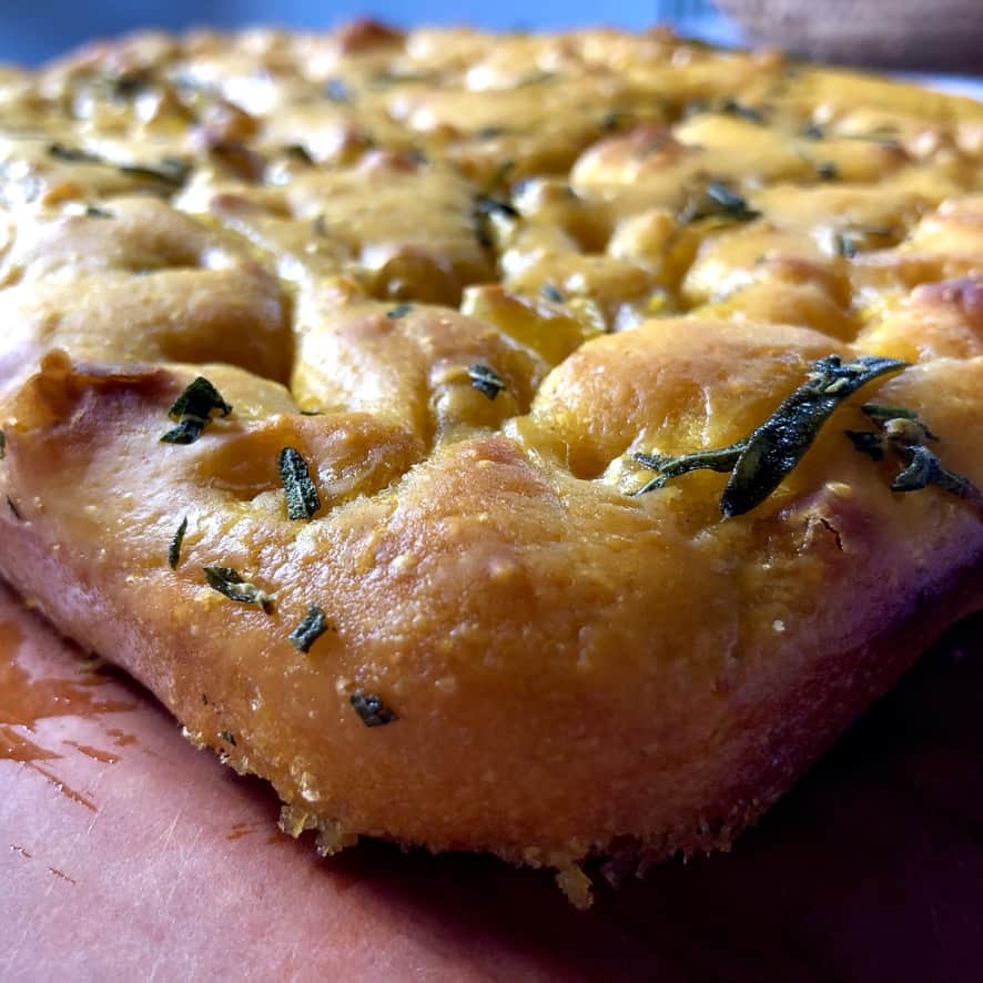 Beautiful orange crispy-edged pumpkin focaccia with rosemary and dimpled everywhere on top.