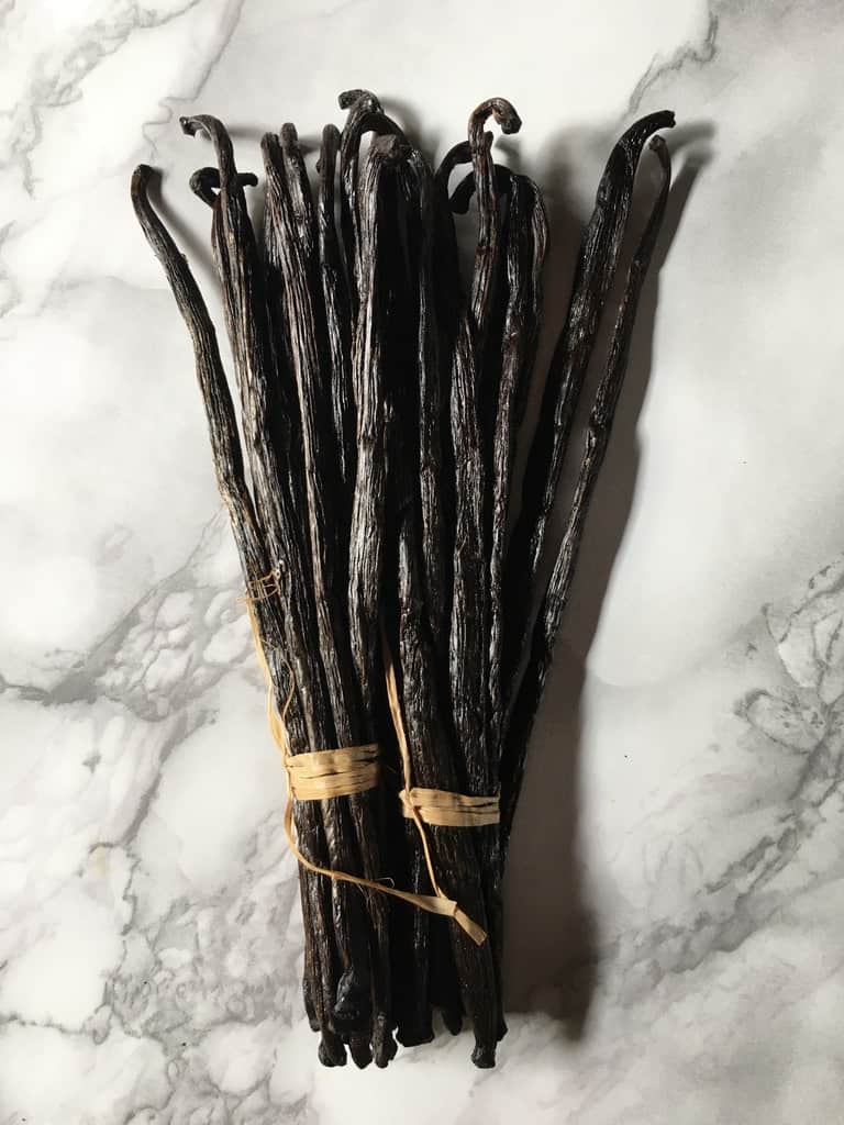2 wrapped bundles of Madagascar vanilla beans with natural twine wrapped around each bundle of 11
