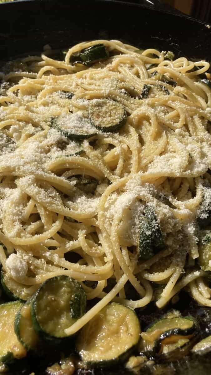 closeup of a braiser dish filled with spaghetti with zucchini and Grana Padano cheese