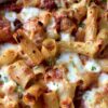 closeup of baked ziti with tomatoes and cheese covered pasta noodles some gooey and some crispy