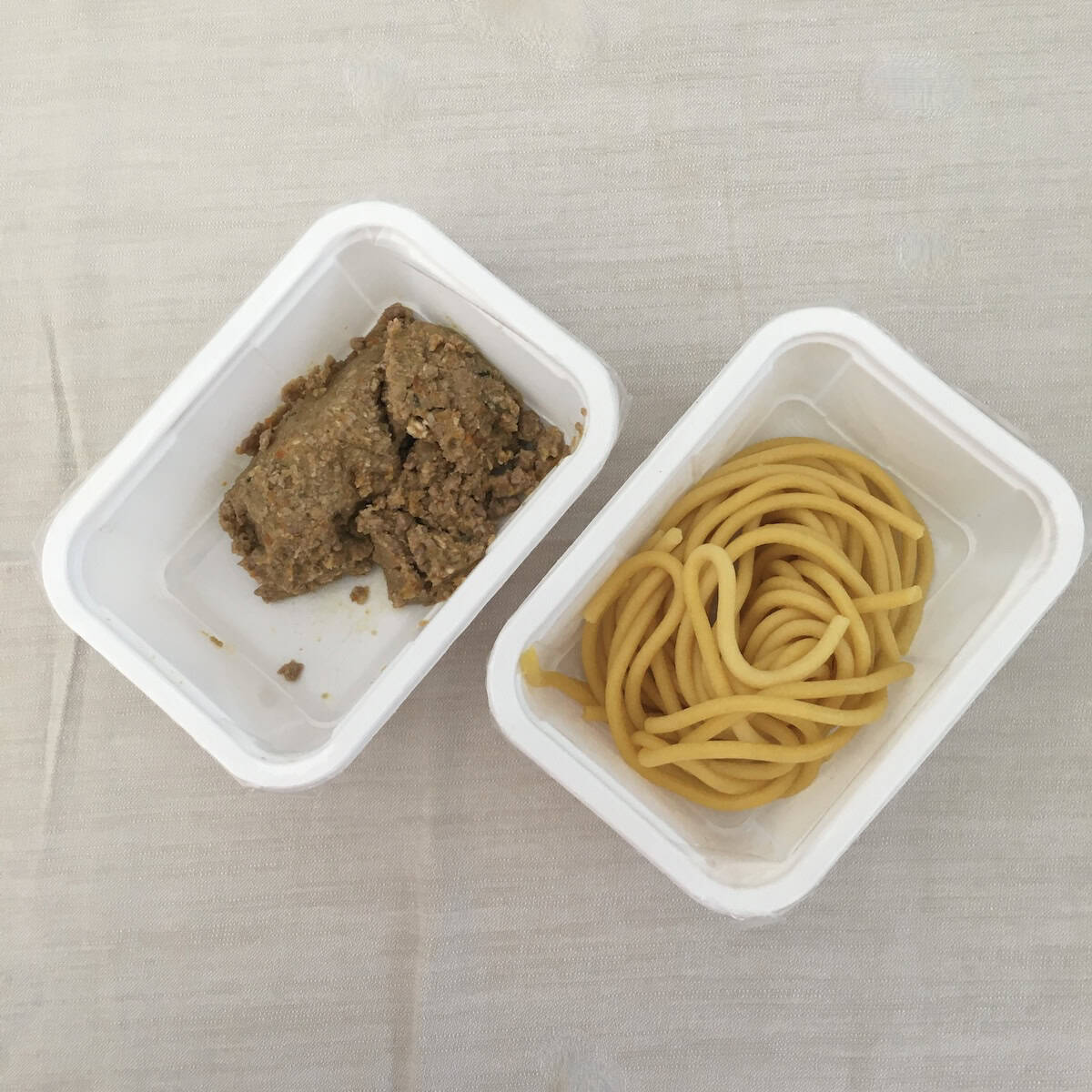 Duck ragu and fresh bigoli pasta in white storage containers from Italian restaurant, pre-made duck ragu ready to reheat and raw bigoli pasta ready to cook, how to store duck ragu for refrigerating or freezing at home.