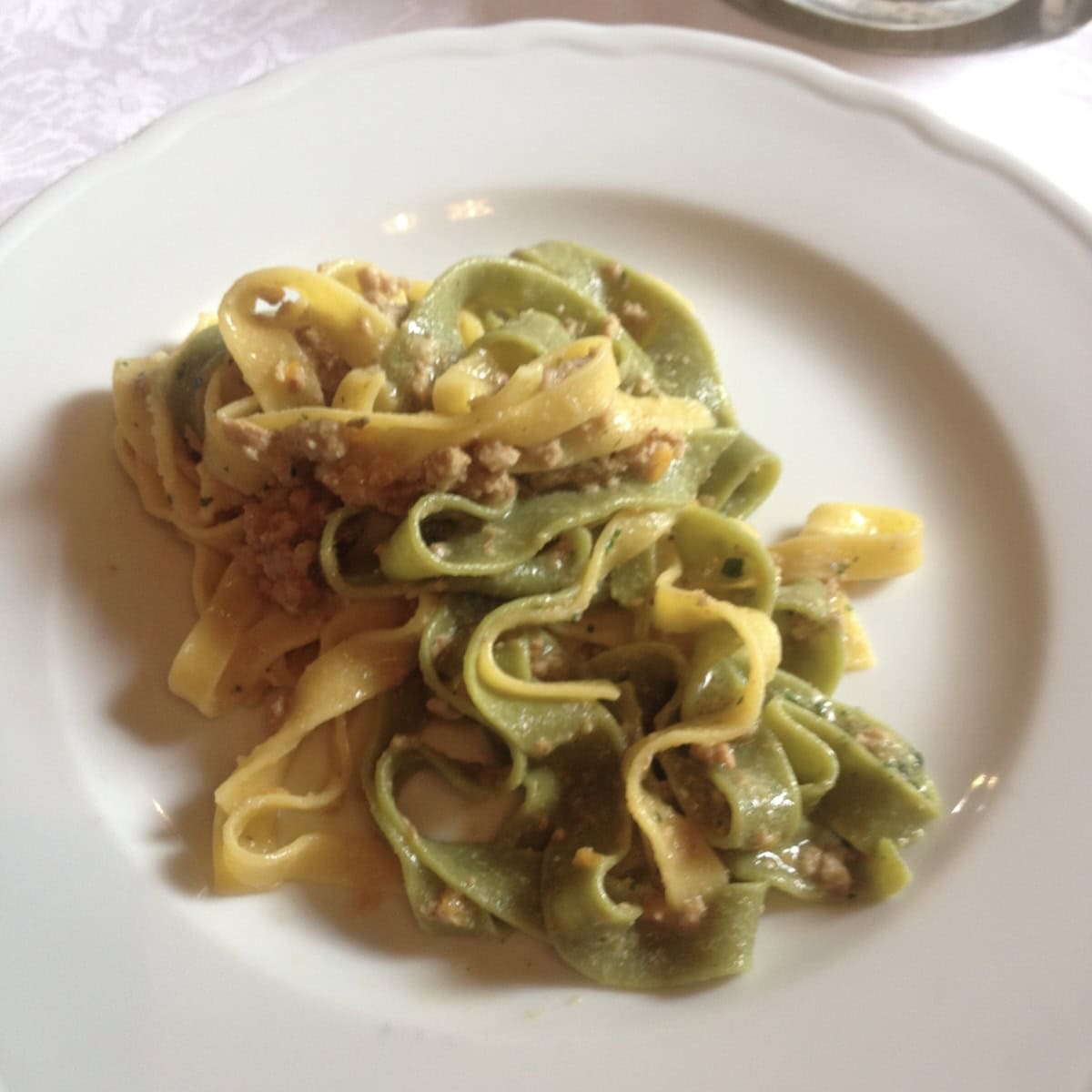 Duck ragu with pappardelle pasta from agriturismo in Northern Italy, italian duck ragu served with regular egg pappardelle and spinach pappardelle pasta, authentic duck ragu pappardelle from Italian countryside restaurant.
