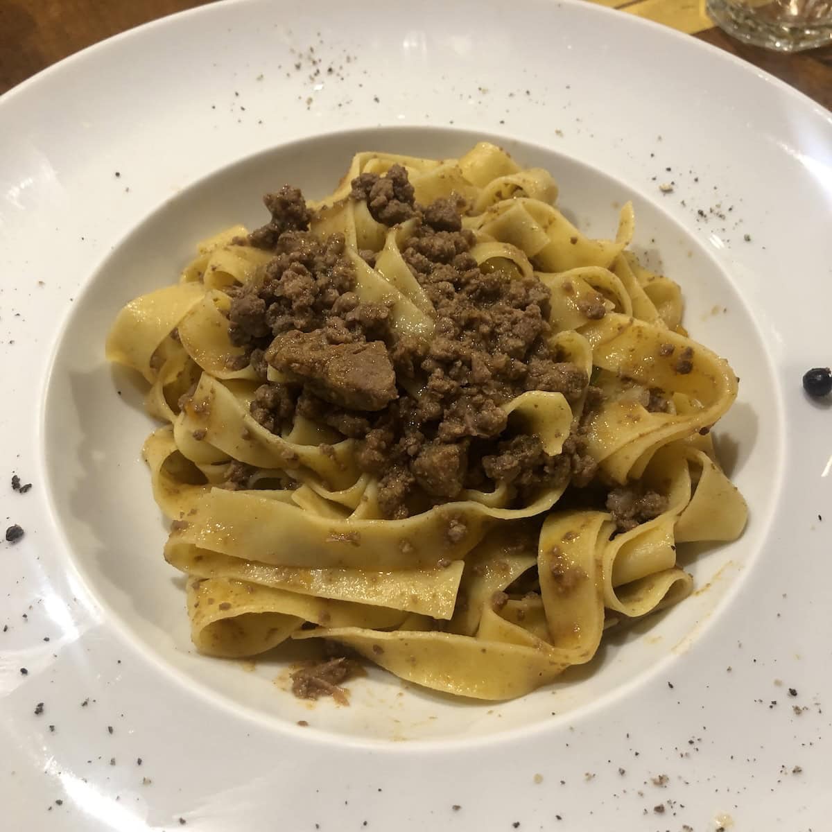 Duck ragu with pappardelle pasta from Northern Italian restaurant, authentic italian duck ragu recipe served at local restaurant in Italy, traditional duck ragu pappardelle plated dish.
