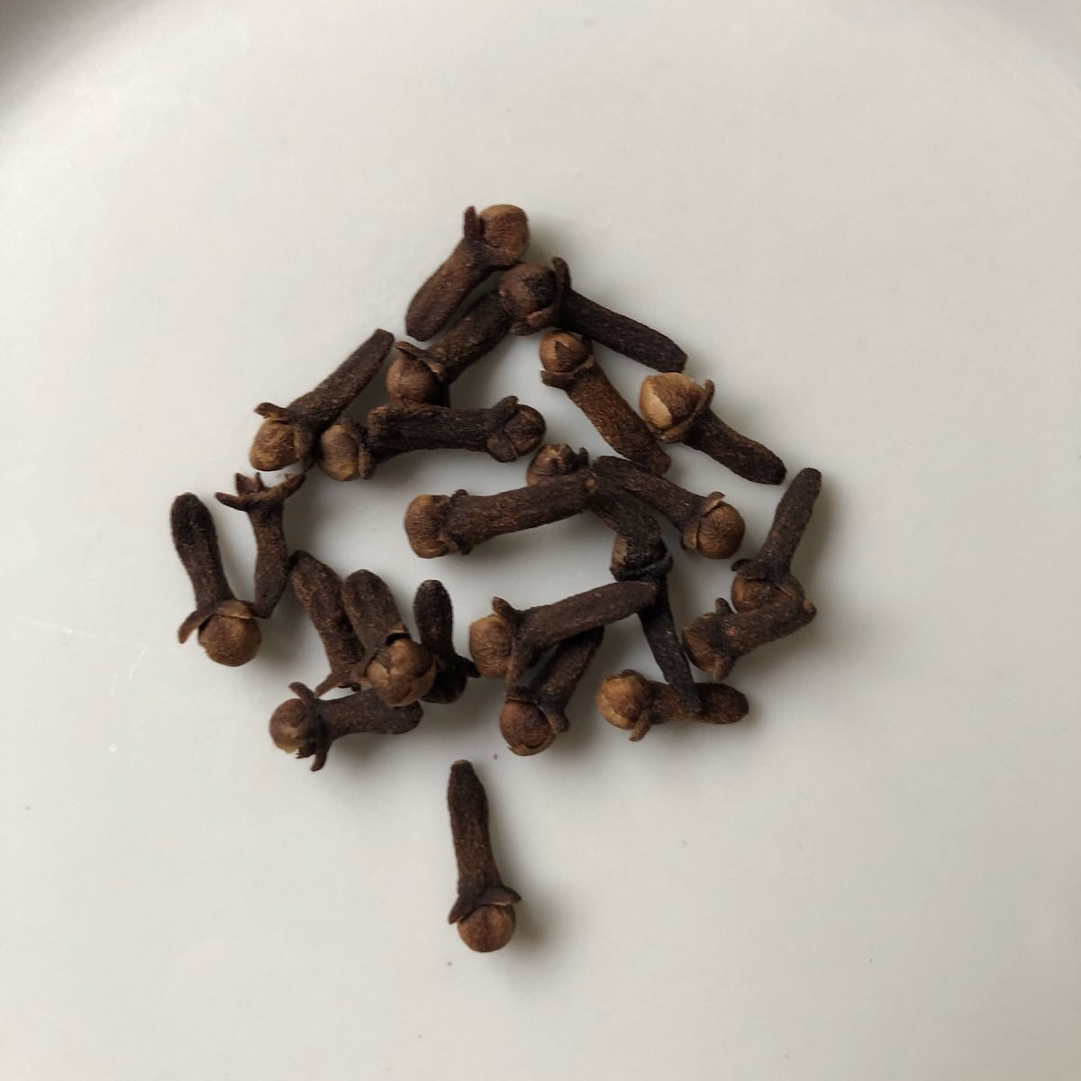Whole cloves on a plate showing how to customize homemade pumpkin spice/pumpkin pie spice.