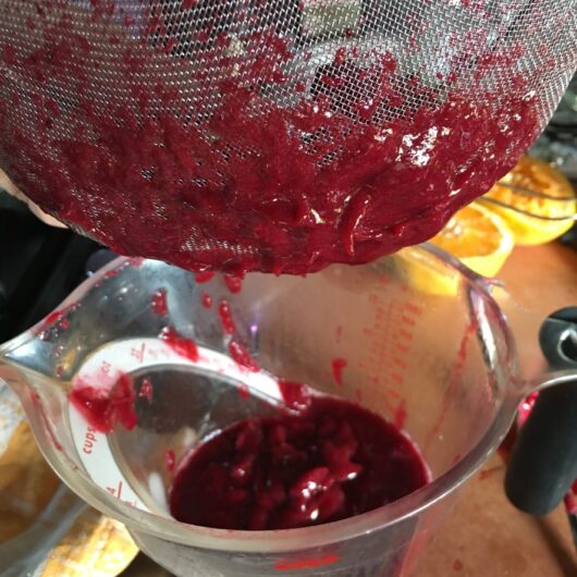 the bottom of the sieve with some fruit sauce that needs to be scraped off the bottom into the strained sauce