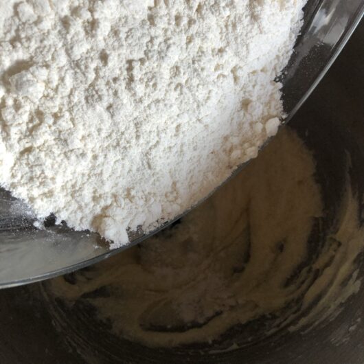 adding flour mixture to creamed butter and sugar mixture