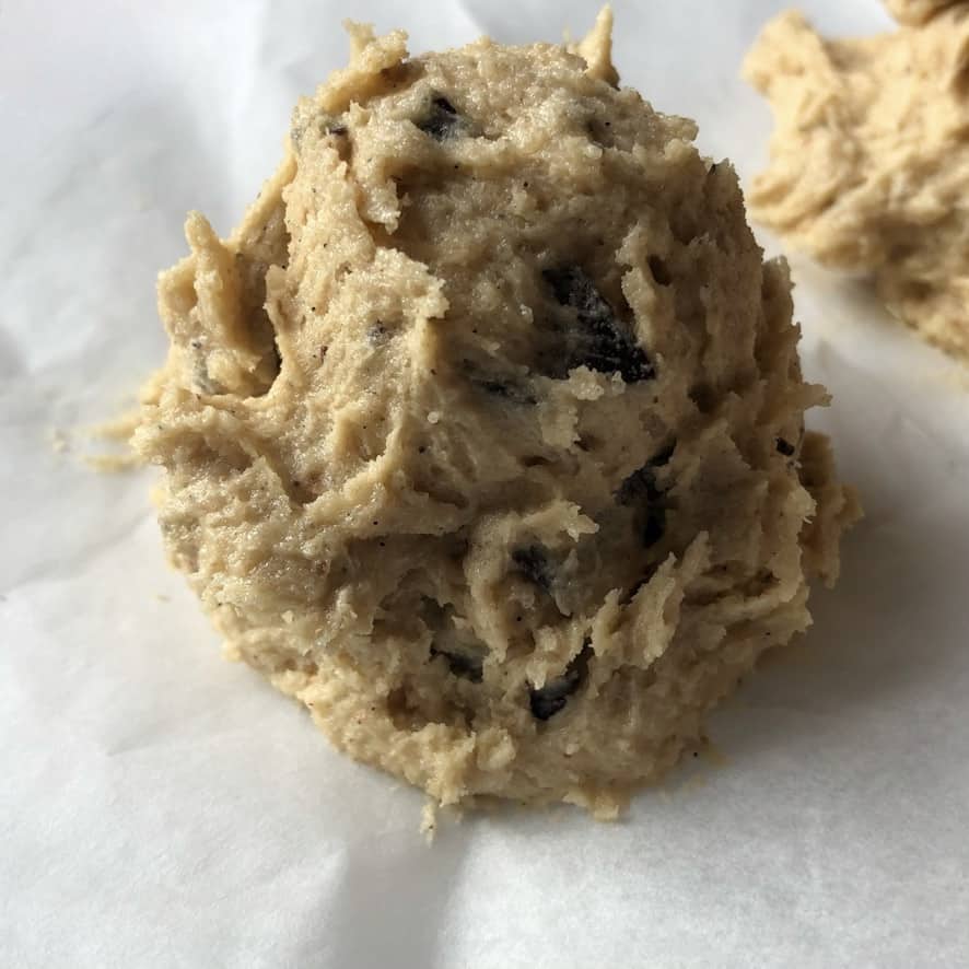 a mound of scooped cookie dough on a parchment-lined baking tray
