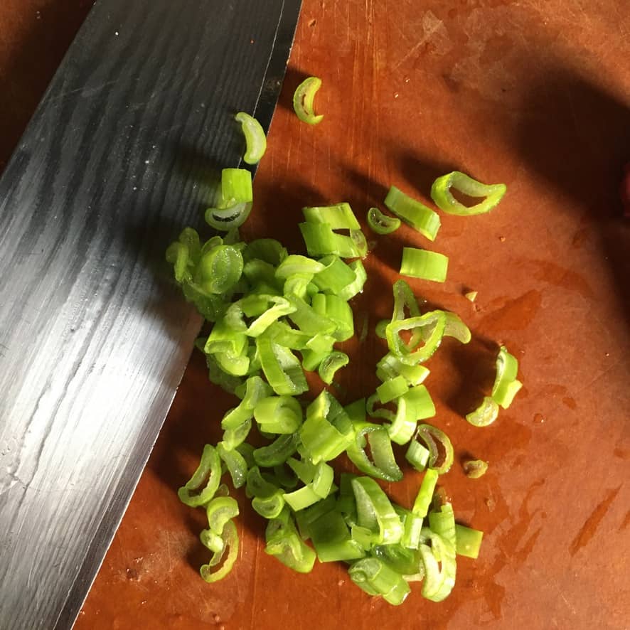 sliced scallions next to a knife on the cutting board