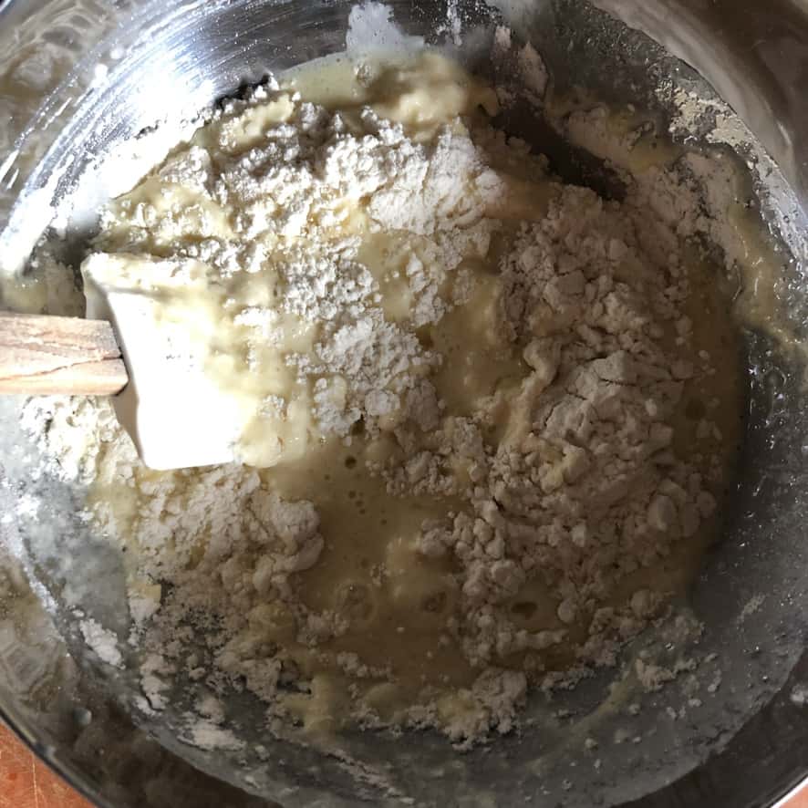 white rubber spatula folding in the wet ingredients into the dry pancake ingredients