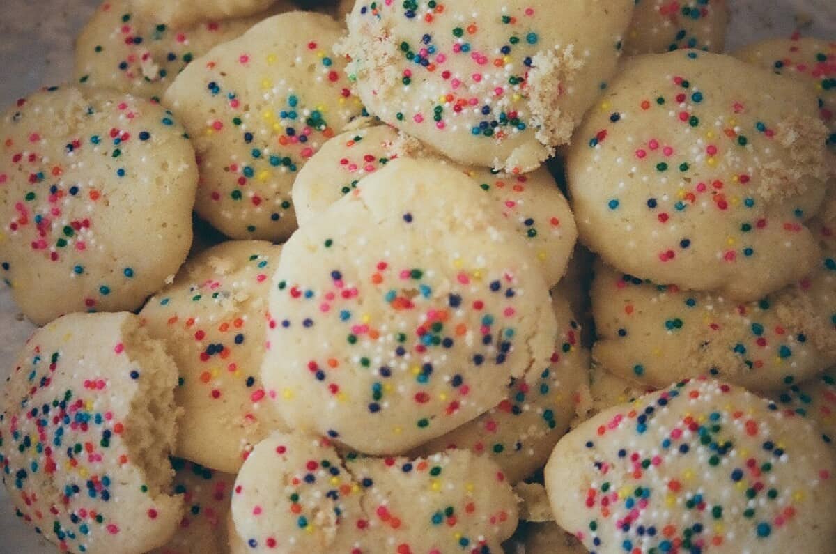 Aunt Donna's famous sugar cookies with nonpareil sprinkles in a pile on a platter and you can only see the cookies, not the platter
