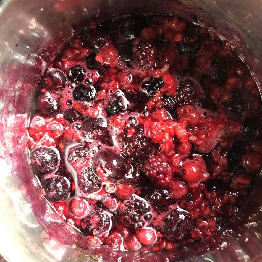 frozen mixed berries that have just started to cook and are no longer frosted, but instead are glossy and brighter than ever and full of juices