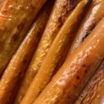 perfectly pan seared long carrot slices glistening with olive oil on a white platter