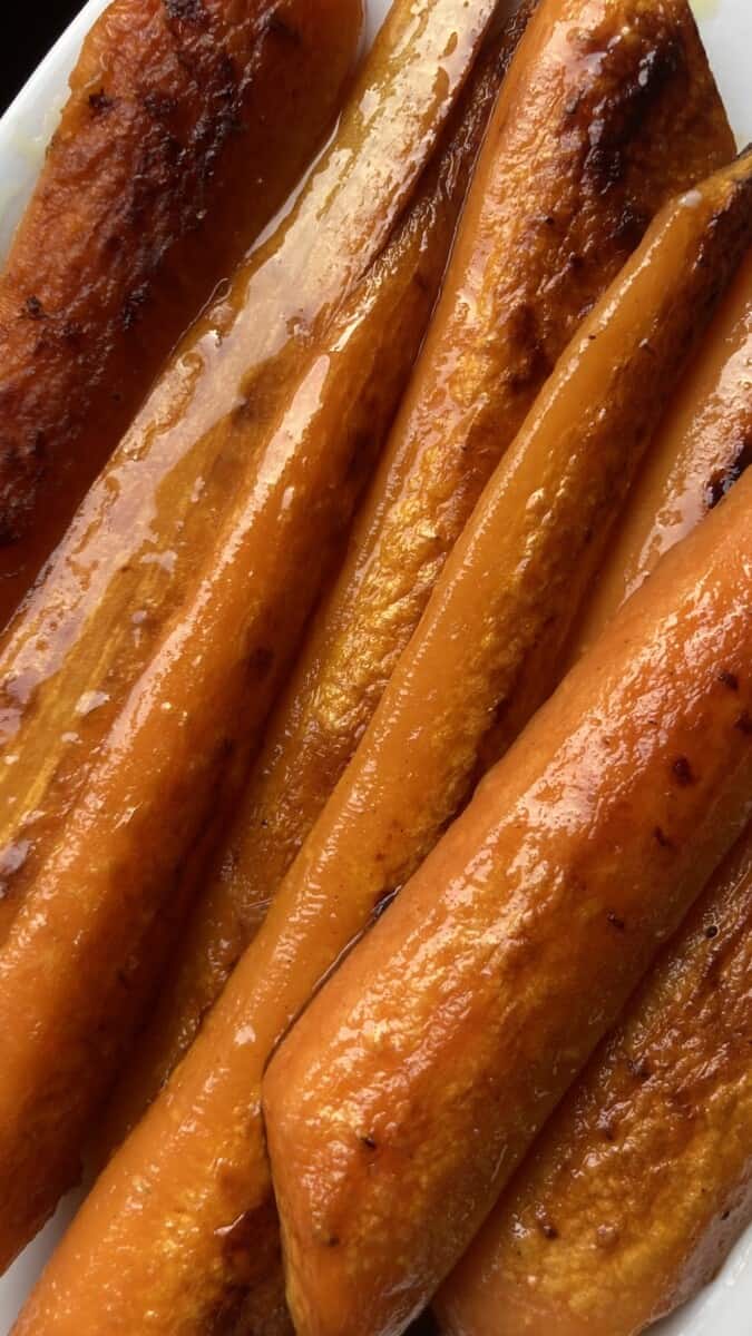 perfectly pan seared long carrot slices glistening with olive oil on a white platter