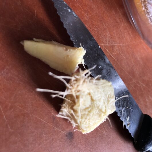 slicing fresh ginger on a cutting board