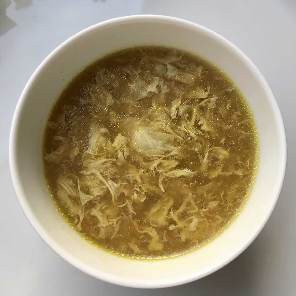 a bowl of glistening a egg drop soup (darker in color because stock was darker and turmeric was added)