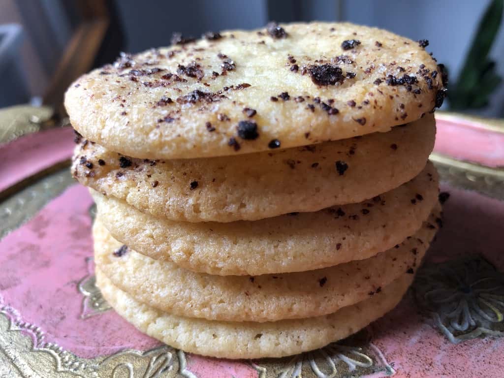 A stack of 5 strawberry lemon sugar cookies on a vintage wood Venetian tray.