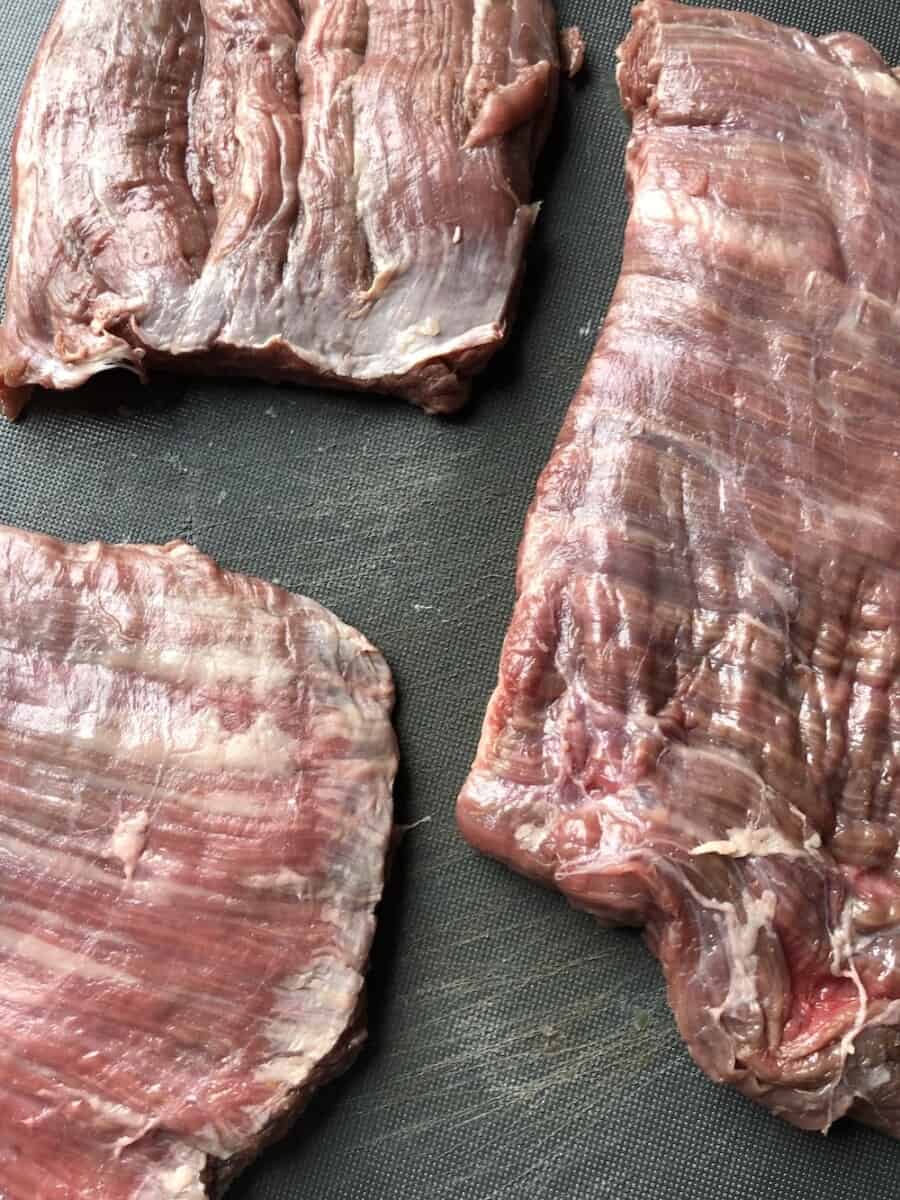 raw flank steak on a cutting board (3 pieces)