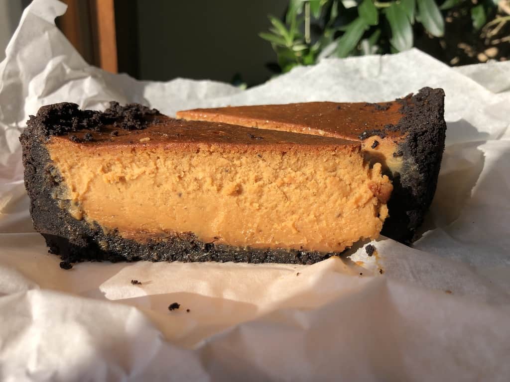 two slices of thawed cheesecake on a piece of parchment paper in the sun and looking like it was just made the day before