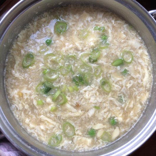 finished pot of egg drop soup with sliced green scallions floating on top