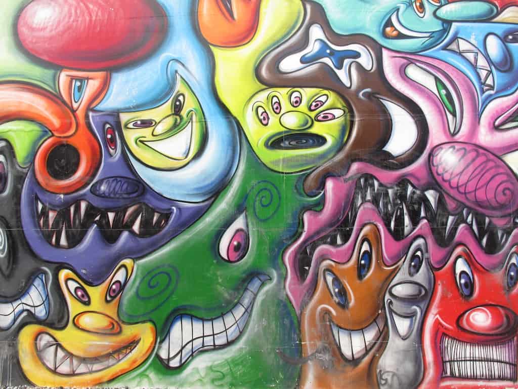 kenny scharf mural on Houston Street in NYC with melting, amazing bright monsters of all colors intertwining with one another in a continuous flow of and endless scenes