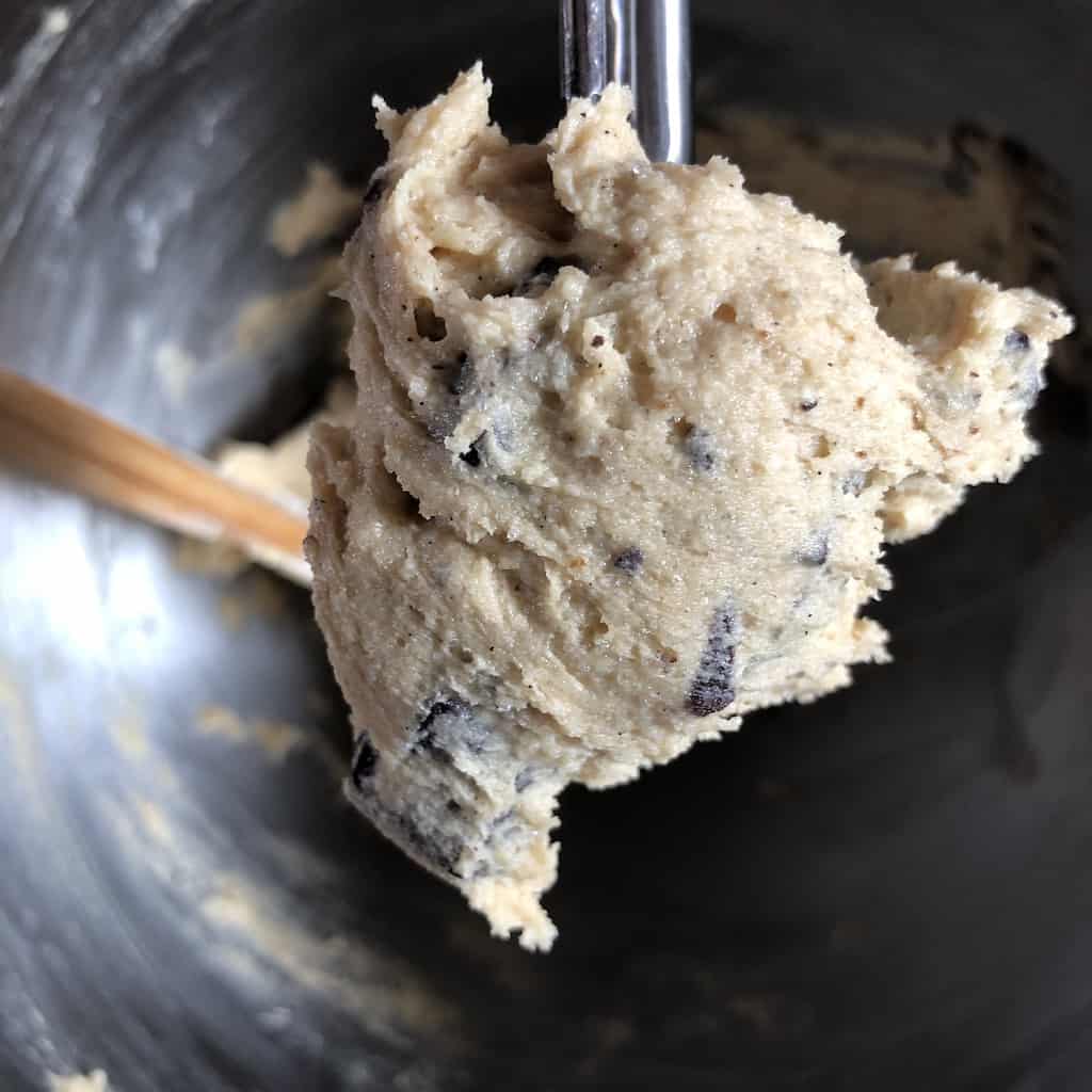 chocolate chip cookie batter being scooped using a metal portioned scooper