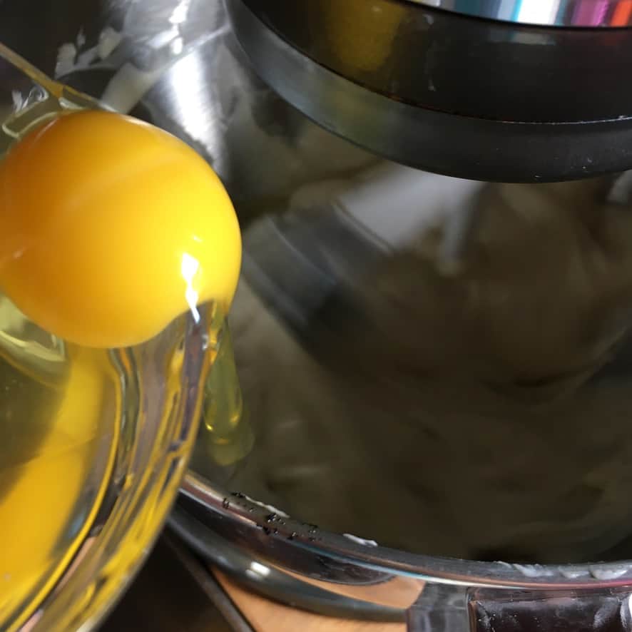 an egg being added to the cheesecake base