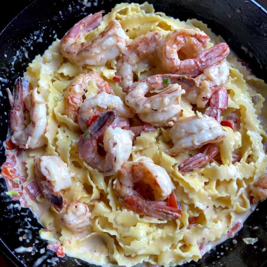 the most delicious creamy shrimp alfredo pasta ready to eat with huge red Argentinian shrimp on top of a zigzag regional egg pasta