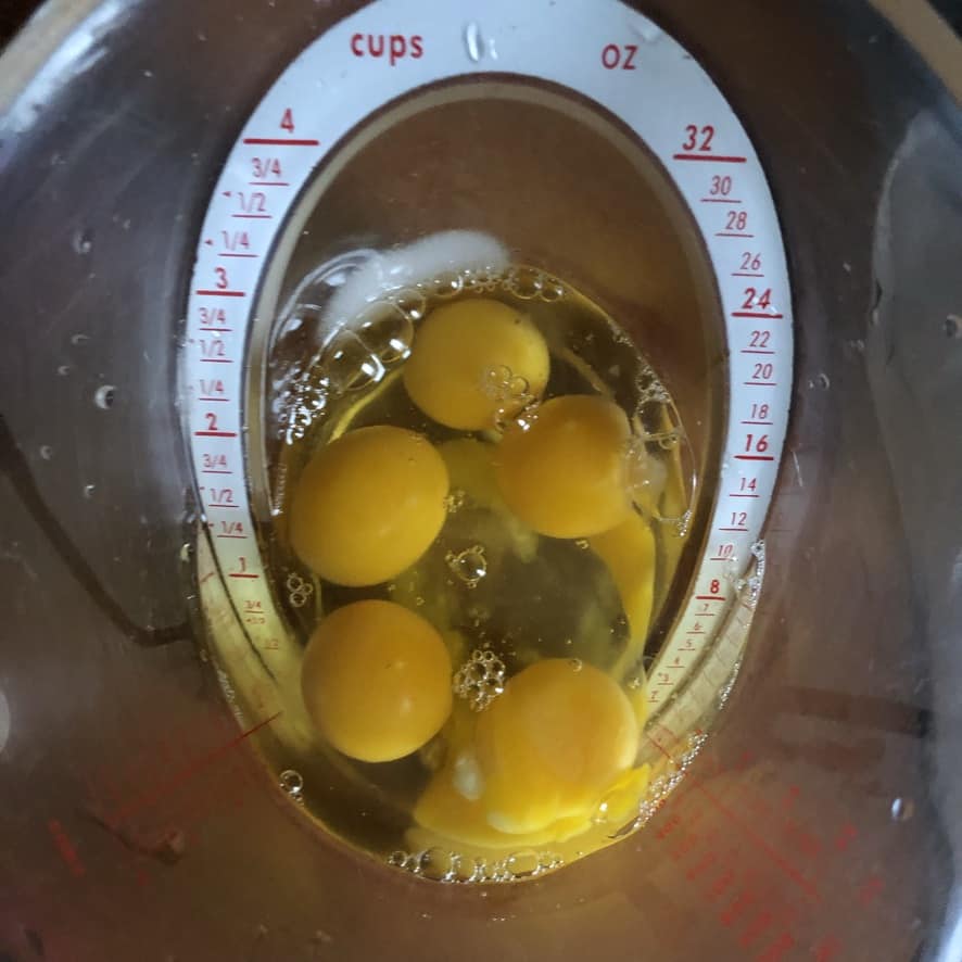 cracked raw whole eggs in an OXO measuring cup
