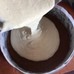 pouring raw vanilla bean cheesecake base into a springform pan