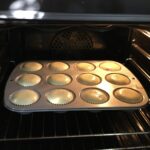 baking mini vanilla cheesecakes in a muffin tin all puffed up and ready to remove from the oven