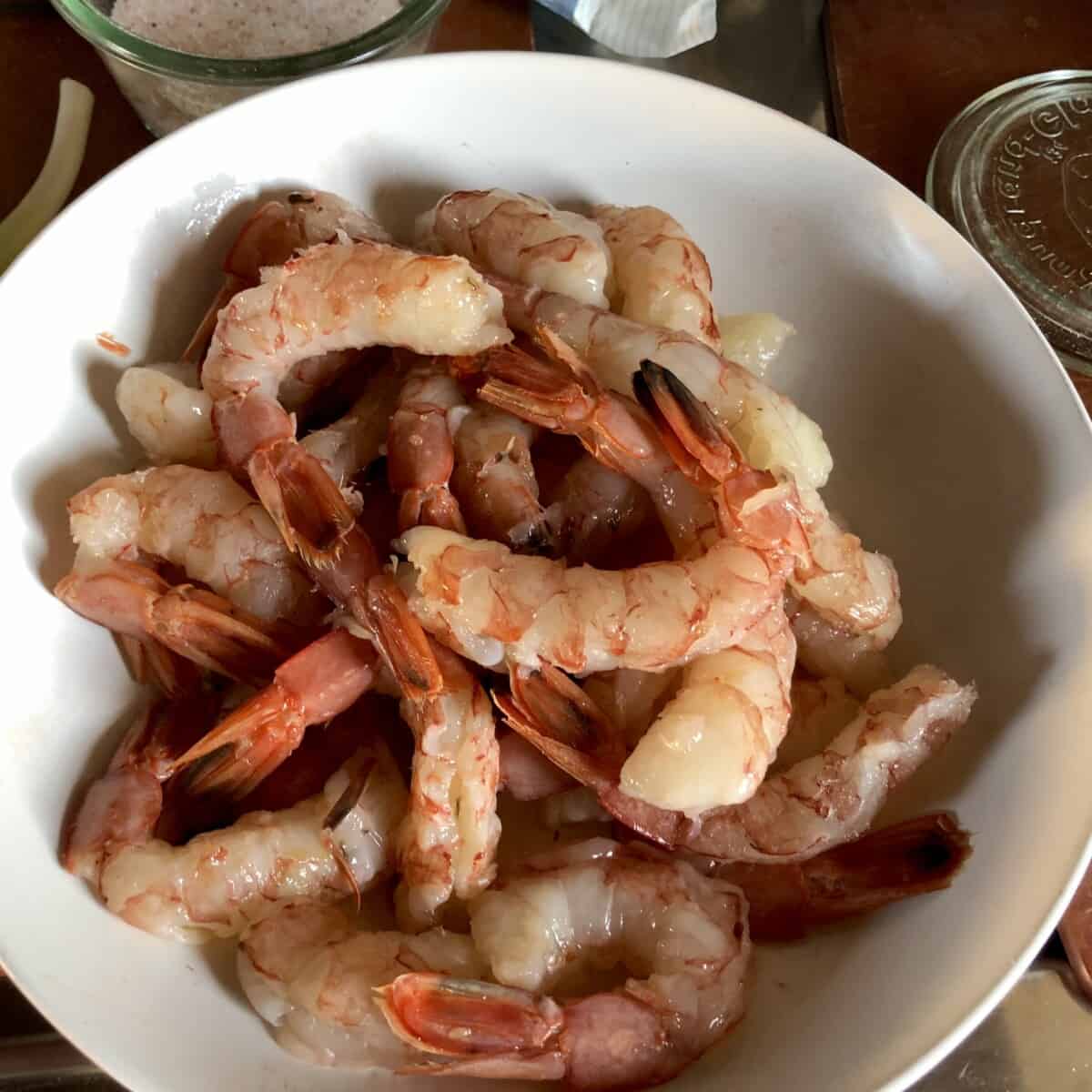 Argentinian red shrimp with shells removed and tails still intact piled high in a white ceramic bowl