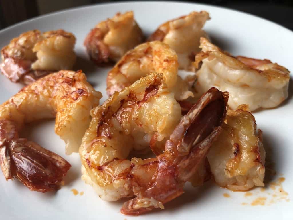 white plate filled with reddish orange perfectly pan seared Argentinian Royal Red shrimp with a golden sear