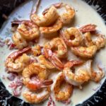 beautiful orange-red perfectly pan seared Argentinian Red shrimp placed on top of a Parmigiano Alfredo cream sauce for