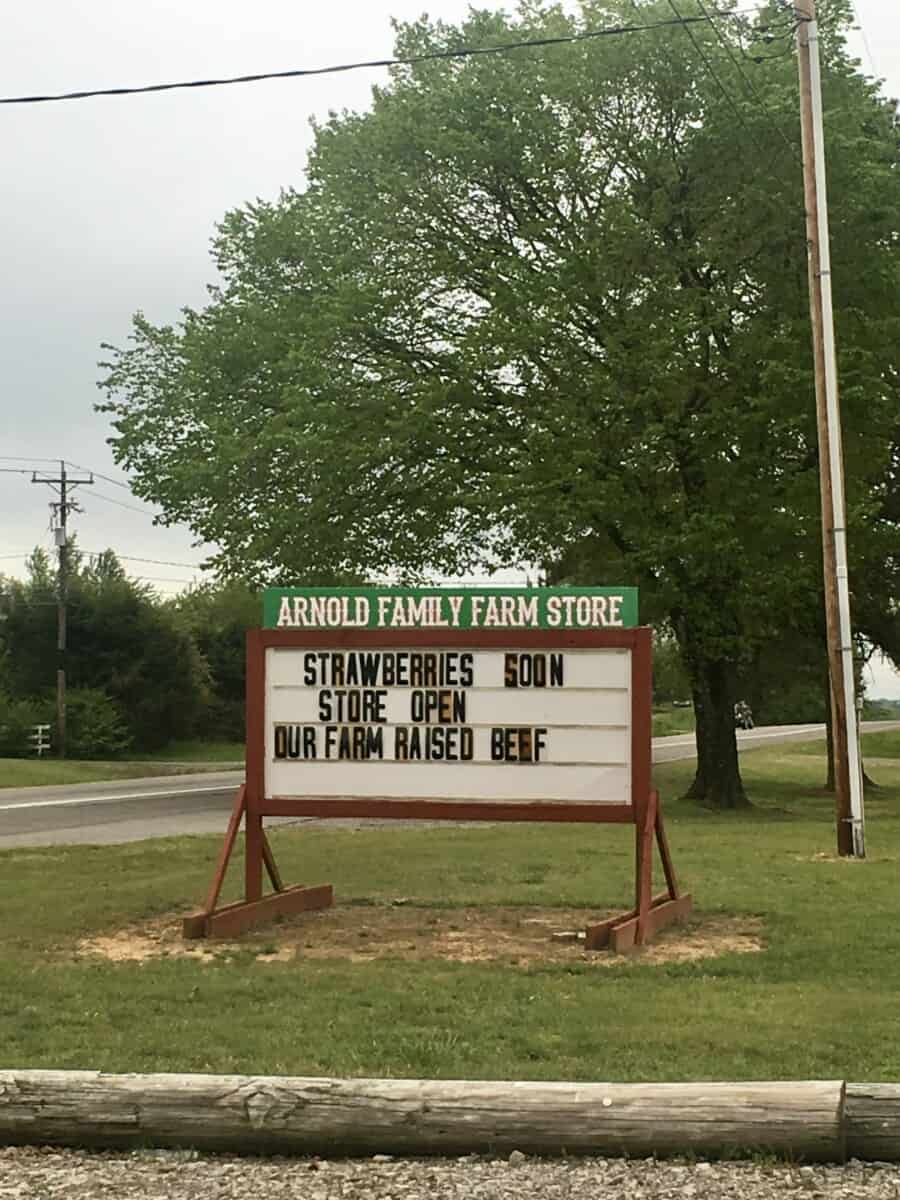 a business sign from Arnold Farm's in Arkansas stating, "Strawberries soon, Store Open, Our Farm Raised Beef