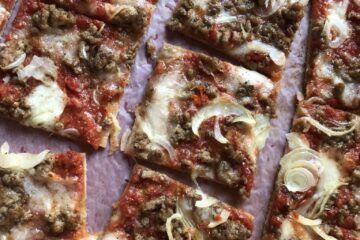 St. Louis Style homemade pork sausage and onion pizza cut into squares