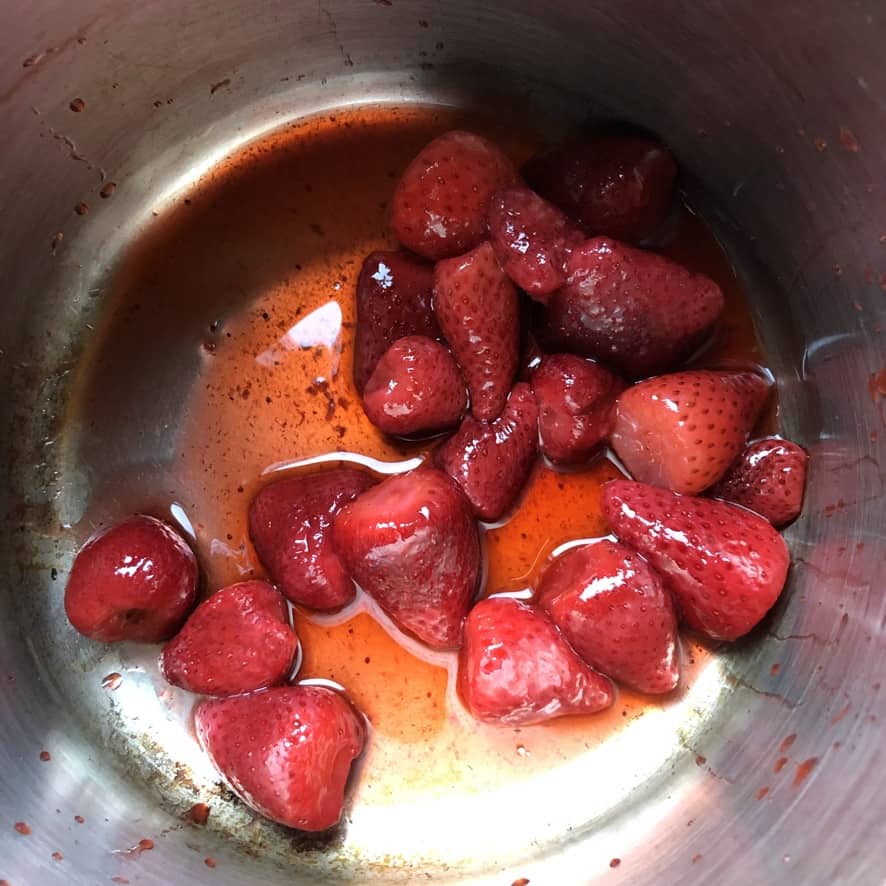 stainless steel pot filled with thawed whole previously frozen strawberries