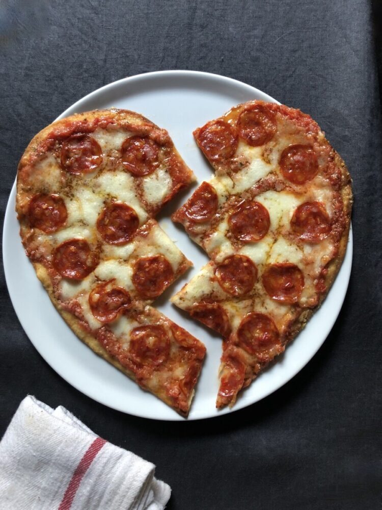 Pepperoni topped pizza in the shape of a heart that's been cut in a zigzag down the middle and slightly separated to reveal a broken heart pizza