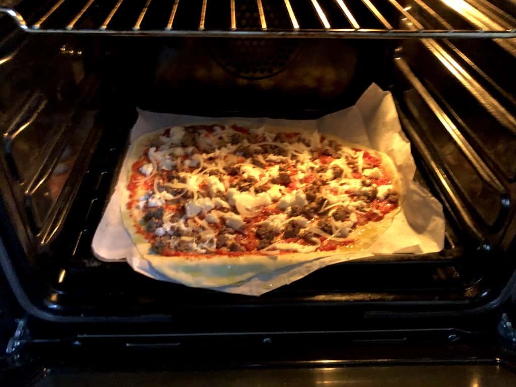 St. Louis Style homemade pork sausage and onion pizza baking in the oven