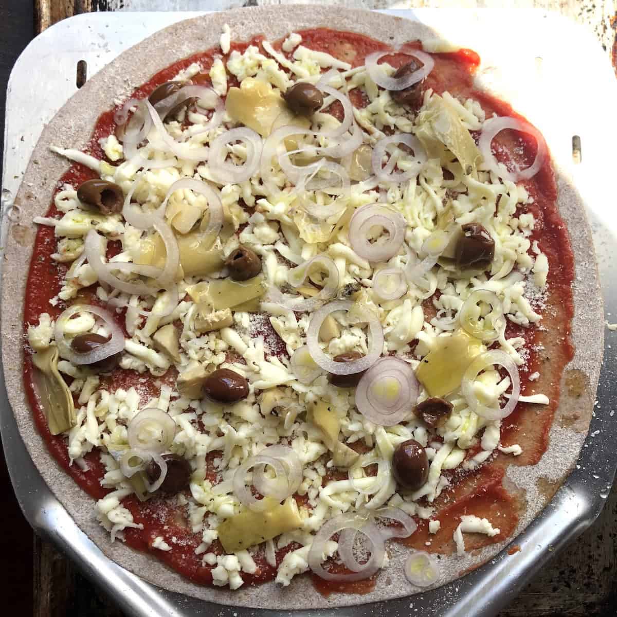 Crispy whole wheat St. Louis style thin crust pizza topped with pizza sauce, melted mozzarella cheese, marinated artichoke hearts, small black meaty Taggiasche olives, and caramelized onions - no yeast pizza recipe.